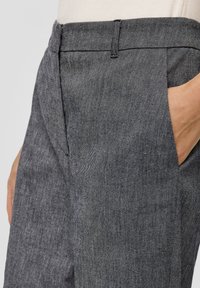 Pantalons gris texturés avec un subtil motif en chevrons, dotés de poches latérales et d'une ceinture structurée.