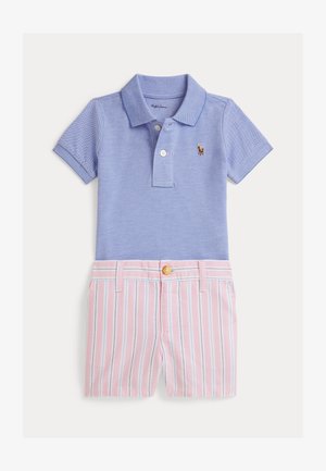 Polo azul claro con un pequeño logo, combinado con pantalones cortos de rayas rosas que tienen detalles en azul y cierre de botón en la cintura.