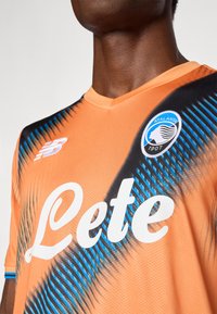Narancssárga sportmezek fekete és kék átlós mintázattal, a mellkasán fehér "Leté" felirattal és klub emblémával. Texturált anyag.