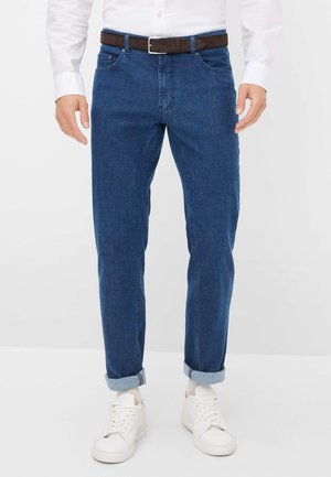 Blauwe denim jeans met een rechte pasvorm, opgerolde onderkanten en een bruine riem. Draagt met witte sneakers. Gladde textuur, klassiek vijf-pocketontwerp.
