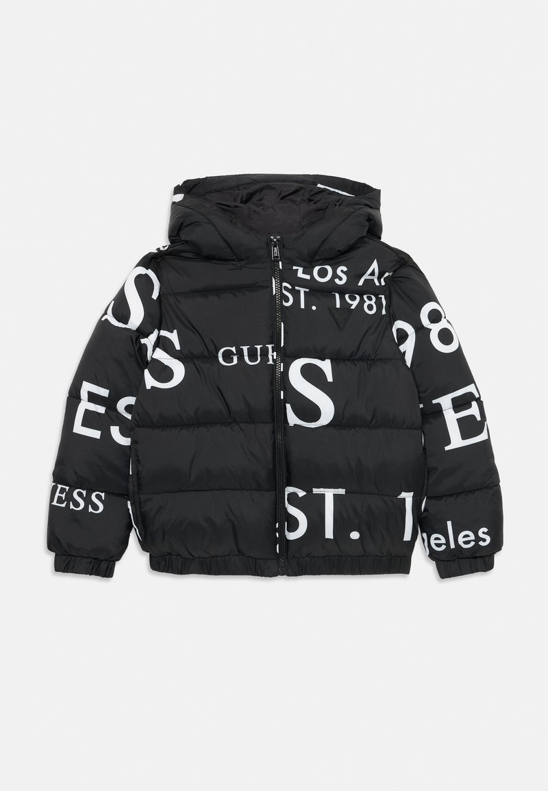 Doudoune noire avec capuche, fermeture éclair à l'avant et motifs textuels blancs, incluant "GUESS," "EST. 1981," avec une texture matelassée.