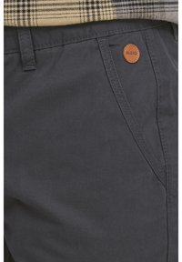 Pantalon gris foncé en coton ; doté de poches angulaires et d'une étiquette en cuir avec le logo "BLEND". Texture lisse et coupe ajustée.