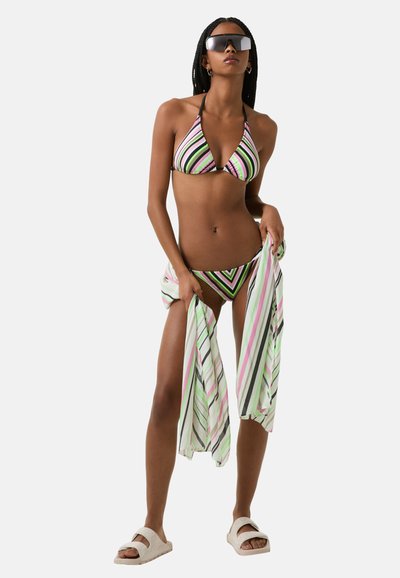 Striped bikini featuring black, pink, and green colors; paired with a lightweight, striped cover-up and white sandals.