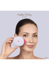 Hello Kitty ansiktsmassager i pastell-lila, ovalt format med ribbad textur, med en liten karaktärsdesign och röd accentetikett.