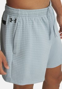 Pantalones cortos azul claro hechos de un material texturizado con un patrón acolchado. Cuenta con una cinturilla elástica, cordón y detalles en negro.