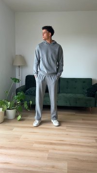 Grauer Hoodie und passende Jogginghose aus weichem Material. Das Outfit hat eine lockere Passform, seitliche Taschen und ein einfaches Design.