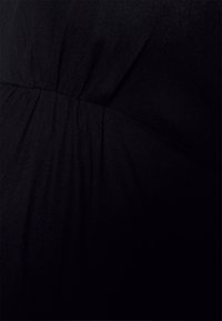 Primer plano de tela negra que presenta una textura suave con detalles fruncidos, destacando un acabado suave y elástico típico de la ropa casual.