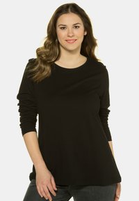 Camiseta negra de manga larga con cuello redondo, confeccionada en una tela suave, con corte relajado y sutiles aberturas laterales en el dobladillo.