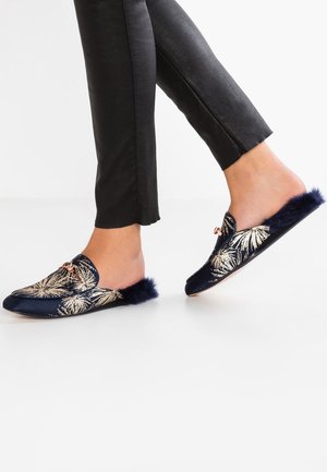 Granatowy kapcie z wzorem złotych liści palmy, futrzanym akcentem z tyłu, płaską podeszwą oraz ozdobną kokardą z przodu.