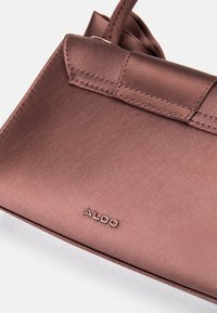 Pruun satiinhüvitis, sileda tekstuuriga, ristkülikukujuline, millel on voltidega klapp ja nähtavad tikandid. Ees on kuvatud "ALDO" logo.