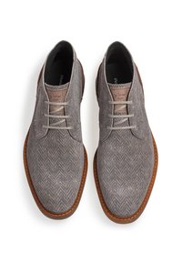 Scarpe grigie con motivo a spina di pesce, finitura testurizzata, dettagli in pelle marrone e lacci grigio chiaro, dotate di punta arrotondata e suola in gomma.