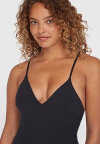 Maillot de bain noir avec un décolleté en V profond, des fines bretelles ajustables et une texture lisse. Le tissu semble élastique et moulant.