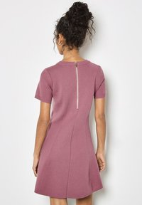 Abito fitted a maniche corte in morbido tessuto lavanda, con scollatura rotonda e zip a vista sulla schiena. Texture liscia, orlo svasato.