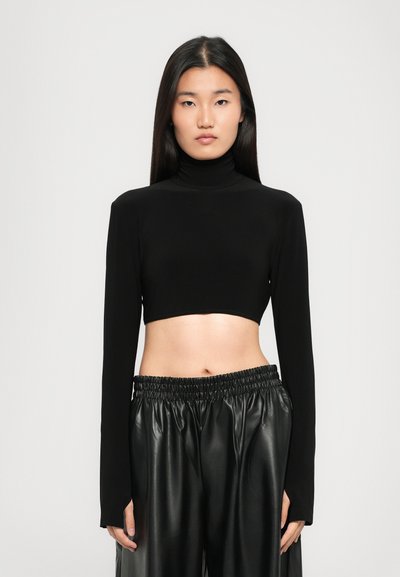 Un pull col roulé noir coupé qui est fait d'un tissu lisse avec des manches longues, associé à un pantalon en cuir noir taille haute avec une taille élastique.