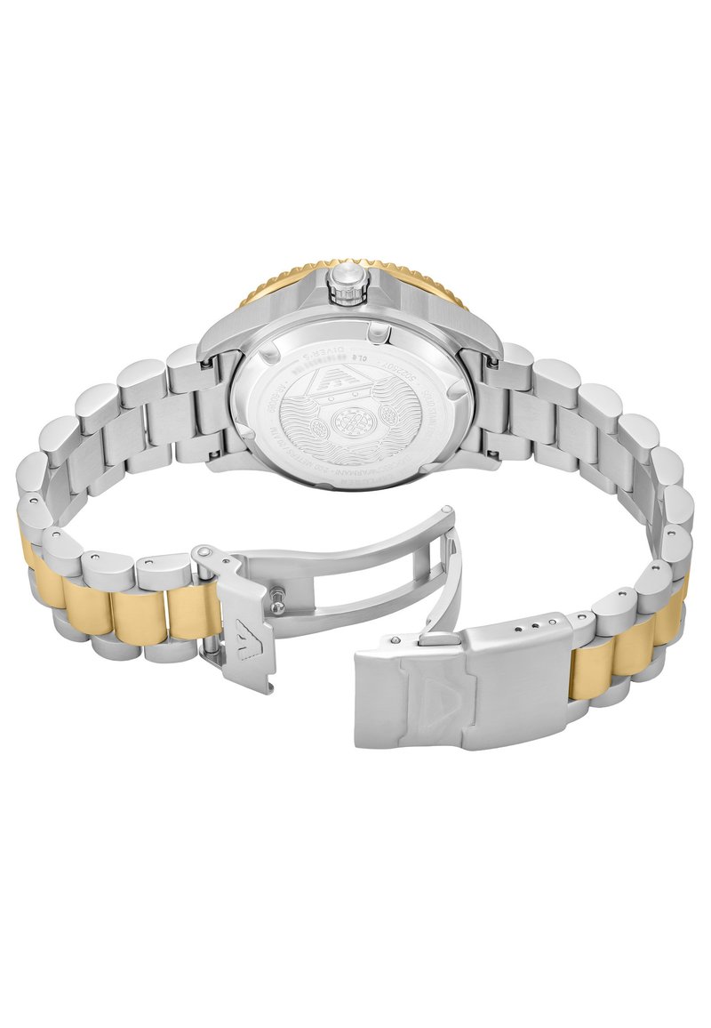 Klocka i rostfritt stål med en band i guldaccent. Har en borstad yta, en texturerad lunett och en spänne med ingraverade logodetaljer.