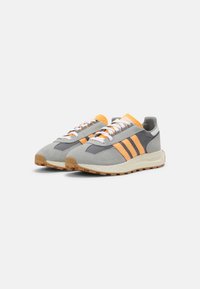 Sneaker grigi con strisce arancioni e lacci bianchi. Realizzati in suede e rete, dotati di una linguetta sul tallone arancione texturizzata e suola in gomma.