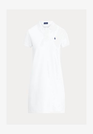 Hvit polokjole laget av bomull, med krage, korte ermer og et marineblått emblem på venstre bryst. Enkel design.