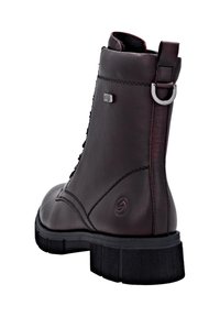 Stivale alla caviglia in pelle marrone con suola in gomma resistente, design con lacci e dettaglio in metallo sul retro. Finitura testurizzata con dettagli sottili.