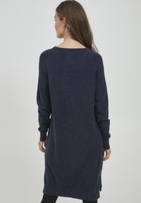 Knälång, mörkblå tröjklänning med långa ärmar, ribbade muddarna, slitsar på sidorna och en bred rund halsringning. Mjuk textur och avslappnad passform.