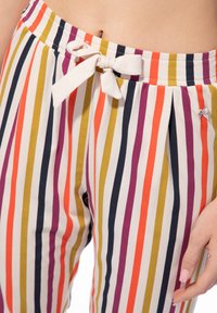 Bunte gestreifte Hosen mit vertikalen Streifen in Orange, Gelb, Lila und Marineblau, mit einer Kordelzugschleife am elastischen Bund.