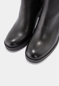 Bottines en cuir noir à finition lisse, bout arrondi et semelle en caoutchouc plate. Présentent une couture discrète le long du bord.