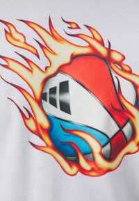 Tricou grafic cu un design de baschet aprins în roșu, albastru și alb, înconjurat de flăcări stilizate portocalii și galbene pe un fundal alb.