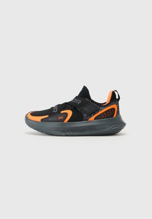 Sort atletik sko med orange accenter, struktureret grå sål, slip-on design med elastiske stropper og mønstret overlay-detalje.