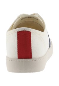 Witte canvas sneakers gezien van de achterkant met een verticale rode streep op de hiel en beige zool details.