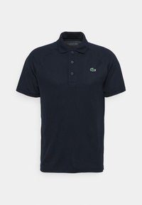 Dunkelblaues Poloshirt aus weichem Stoff, mit einer Knopfleiste mit drei Knöpfen und einem charakteristischen grünen Krokodil-Logo auf der linken Brust.