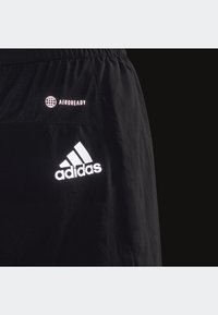 Pantaloni corti sportivi neri in tessuto leggero, con pannello in rete e logo riflettente Adidas con branding "AEROREADY" sulla vita.