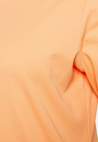 Oranssi lyhythihainen T-paita, joka on valmistettu pehmeästä ja joustavasta puuvillamateriaalista. Ominaisuuksina sileä pinta ja klassinen pyöreä kaula-aukko.