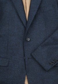 Marineblauwe herringbone blazer van gestructureerde stof met een enkele knoopsluiting, notch revers en twee zijzakken.