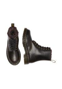 Botas de cuero marrón hasta el tobillo con forro de pelo, punteras redondeadas, seis ojales de metal y costura amarilla en la suela. Suelas de goma planas con agarre.