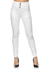 Jeans blancos ajustados con cintura alta, que cuentan con cuatro botones, bolsillos delanteros y una textura suave. Combinados con tacones altos negros.