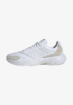 Biały sportowy sneaker z perforowanymi bokami, jasnoszare zamszowe akcenty na czubku i pięcie, zapinany na sznurowadła, z grubą białą podeszwą.