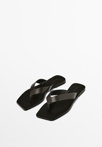 Black flip-flops with a flat sole, featuring two crossed straps in smooth leather and a textured footbed for grip and comfort.