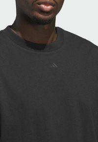Sort bomulds-sweatshirt med rund halsudskæring, der har en diskret sort logo-detail på brystet og en glat tekstur.