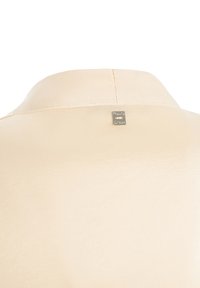 Blusa corta a maniche corte color beige pallido, texture satinata liscia, colletto classico, con un piccolo logo in argento sul retro.