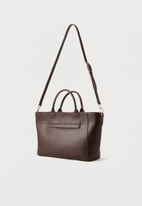 Bolsa tote de couro castanho com duas alças superiores e uma alça de ombro destacável, apresentando um bolso frontal plano e detalhes de costura mínimos.