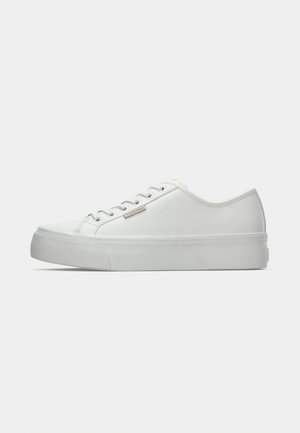 Sneaker bianco a basso profilo con suola spessa, design con lacci e piccolo logo "Calvin Klein" sul lato, mostrato di profilo su uno sfondo semplice.