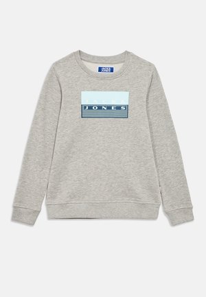 Sudadera de manga larga en gris claro con cuello redondo, con un parche rectangular azul con el logo y el texto "JACK & JONES" en el pecho.