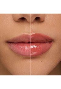 Produit de gloss à lèvres présenté sur un visage divisé : le côté gauche présente un gloss rose pâle ; le côté droit montre un gloss corail plus profond. Les deux ont une finition brillante et lisse.