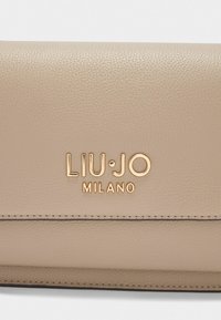 Beżowy skórzany portfel o strukturalnej fakturze, z wytłoczonym na złoto logo "LIU•JO MILANO" oraz starannie przeszytymi brzegami.