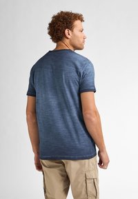 Námořnická modrá tričko s krátkým rukávem, které má kulatý výstřih, strukturovanou tkaninu a mírně vybledlý gradientový efekt. Volný střih.