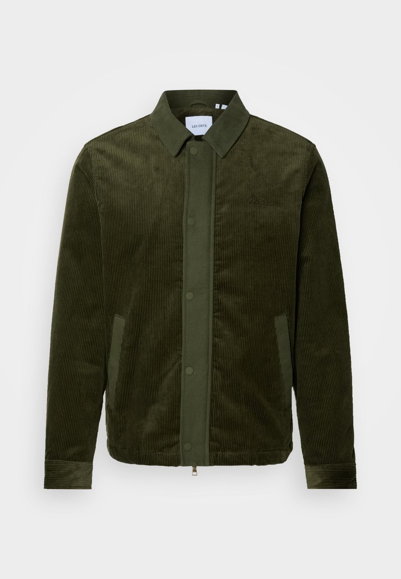 Olivgrüne Cord-Jacke mit Knopfleiste, zwei seitlichen Taschen und einem Kragen. Verfügt über eine vertikale Textur und ein Logo auf der linken Brust.