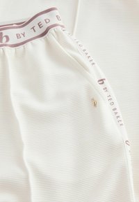 Witte geribde stofshorts met een lavendel tailleband met de tekst "b by TED BAKER" en een klein gouden logo detail.