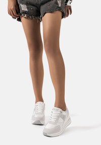 Sneakers bianchi con un mix di texture lisce e scamosciate, caratterizzati da una punta arrotondata, design con lacci e branding sottile sulla linguetta.