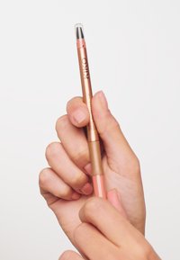 Dobbeltendt sminke blyant med en bronse metallisk kropp. Den ene enden har en rosa blyantspiss med et klart lokk; den andre enden har en svart børste.