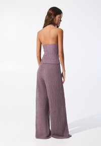 Lyslilla to-delt outfit med en stropløs top og bredbenede bukser, der har tekstureret stof og en smocked design.