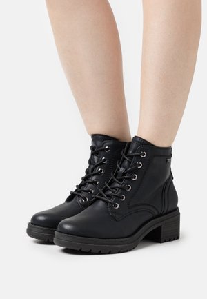 Bottes noires en cuir avec un bout rond, design à lacets, œillets en métal et un talon bloc texturé. Fini lisse avec des détails de surpiqûres contrastants.
